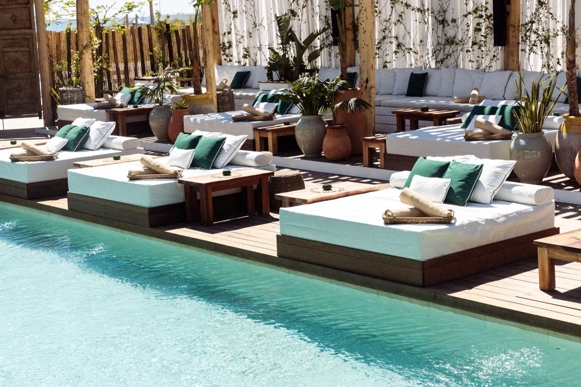Exclusive beach club with poolside daybeds and turquoise water