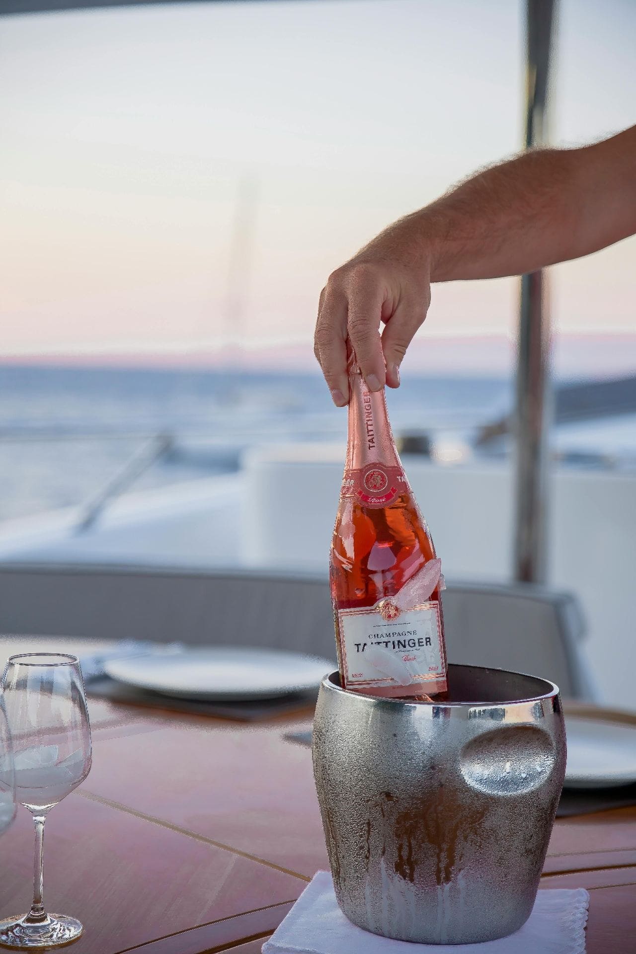 Rose champagne being placed in ice bucket on yacht table
