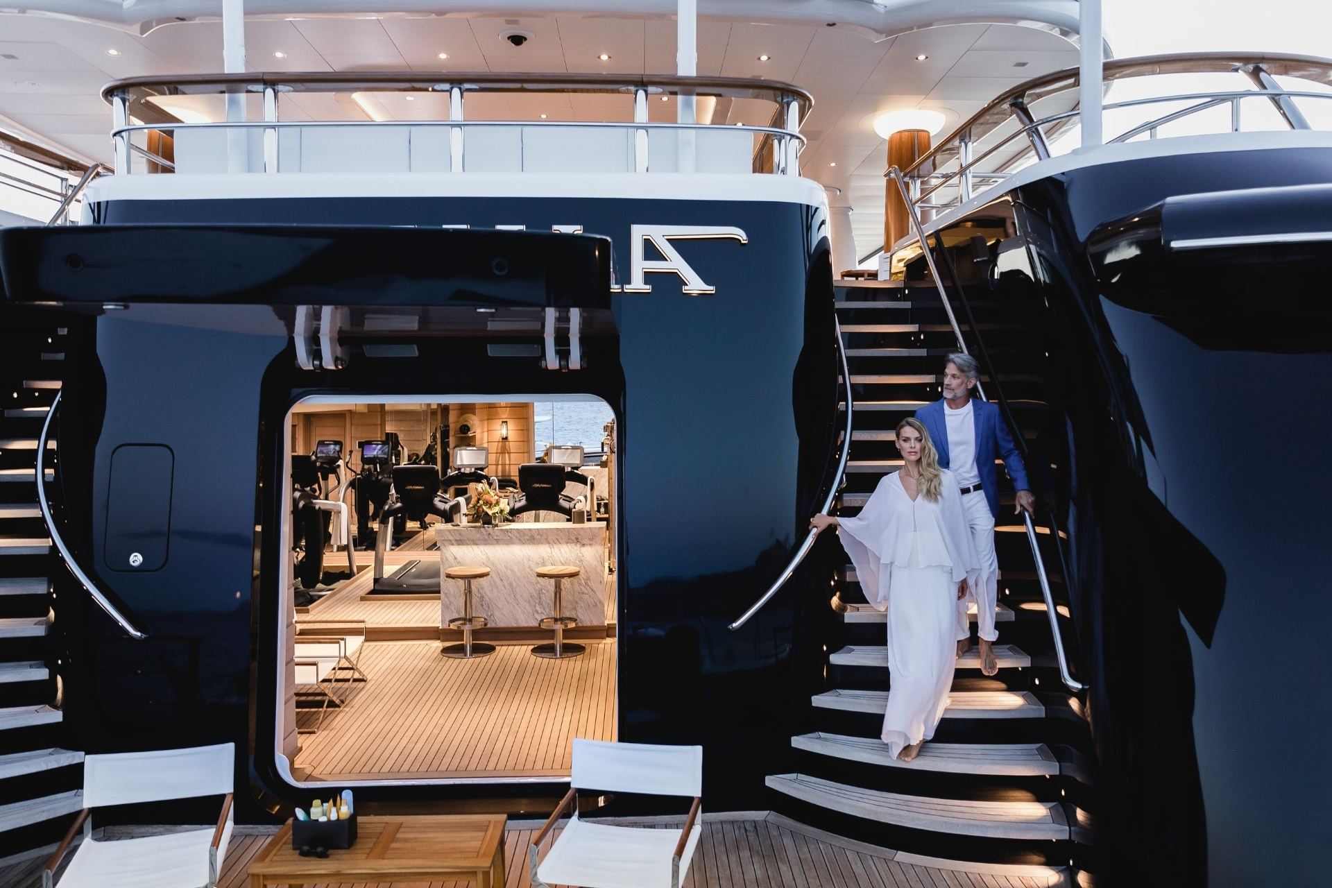 Elegant couple descending superyacht staircase at dusk