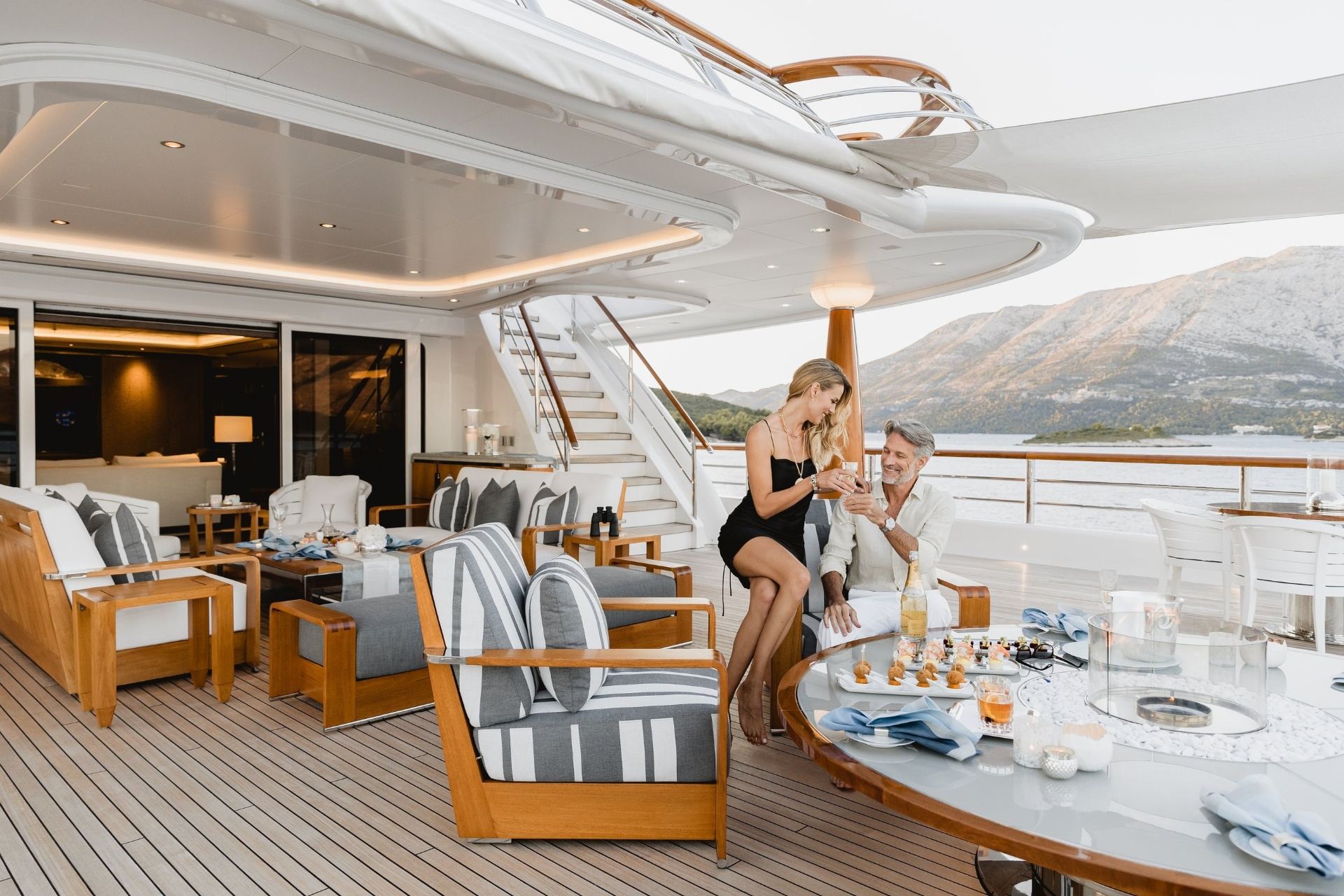 Couple enjoying drinks on luxury yacht deck at sunset