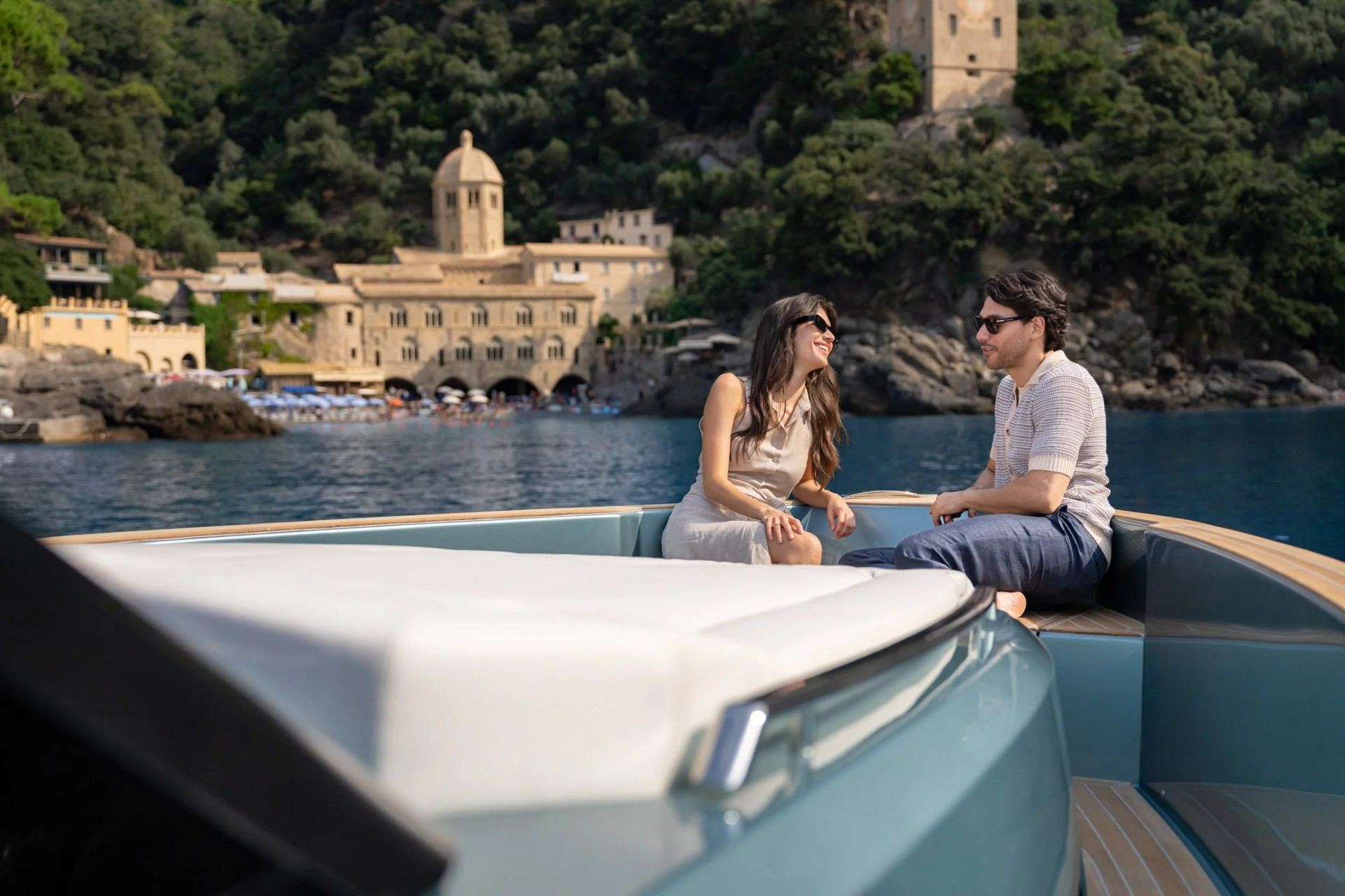 Couple relaxing on Pardo 43 bow lounge near coastal village