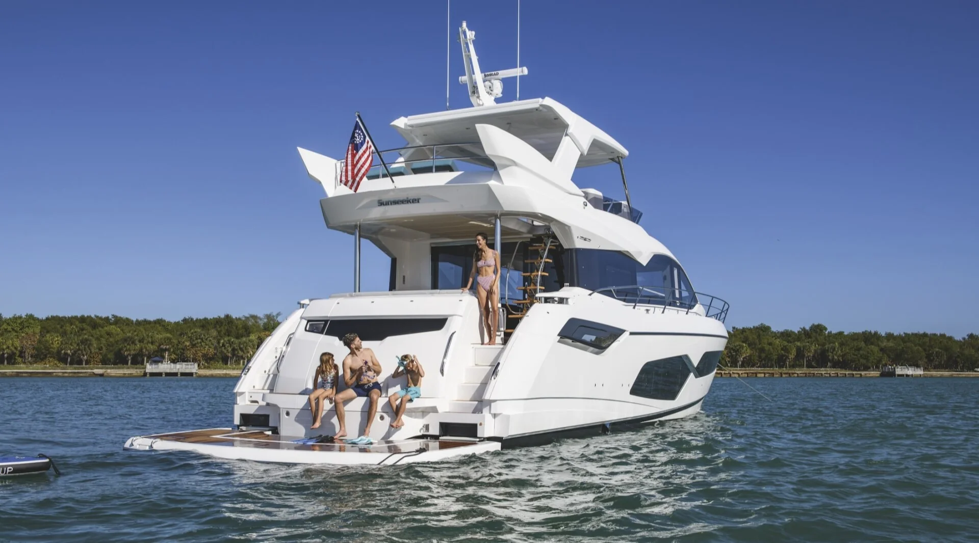 Family enjoying swim platform on Sunseeker yacht at anchor