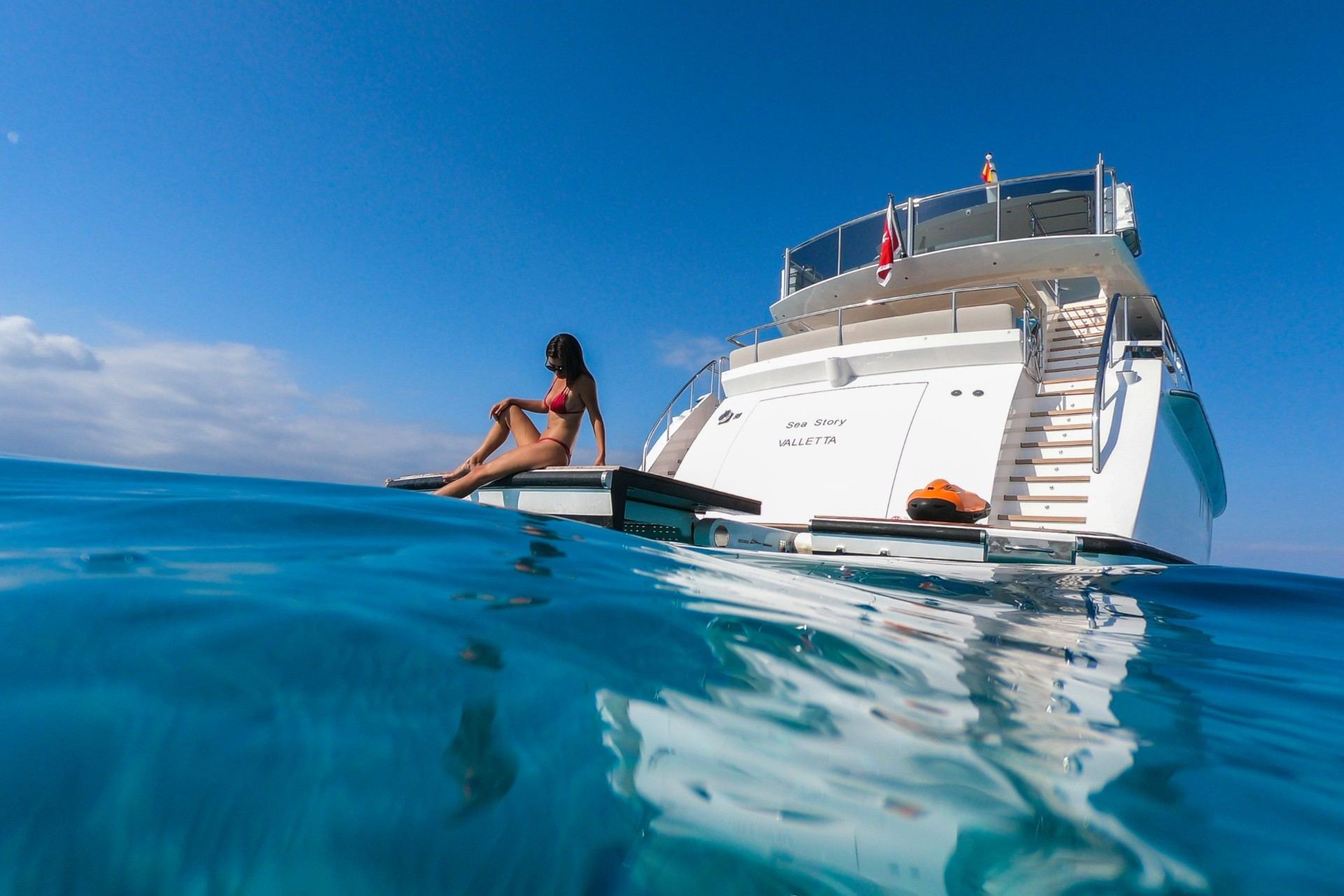 Woman relaxing on superyacht swim platform at water level